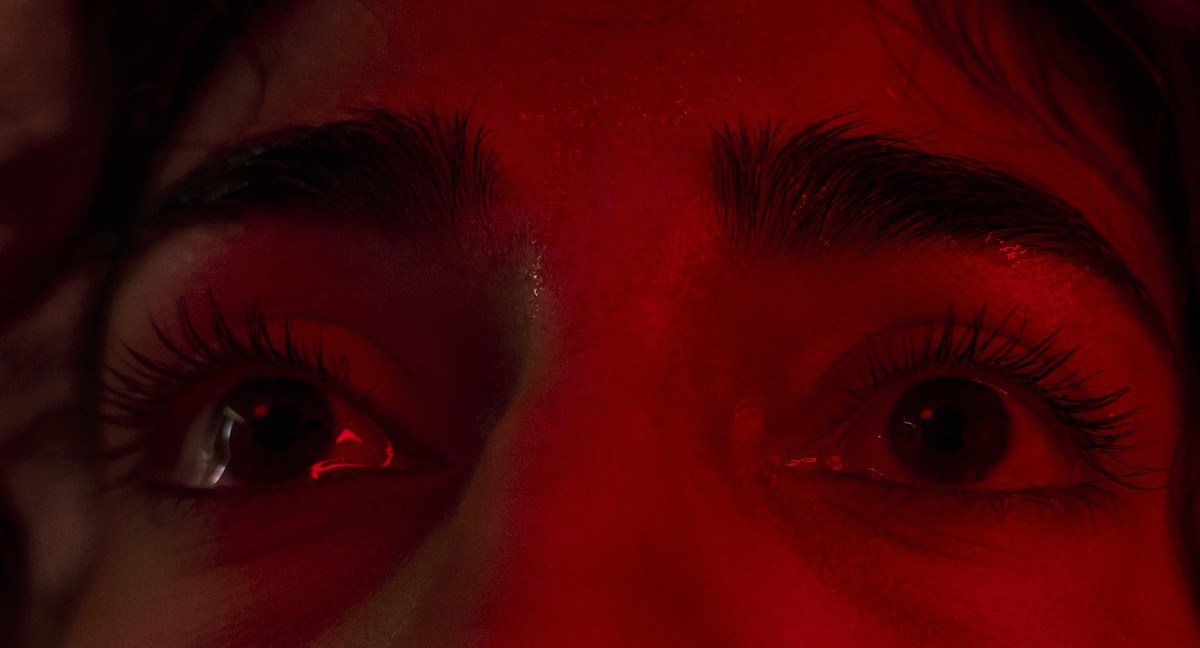 Extreme close-up of the Actor's eyes, wet and lit hard red.