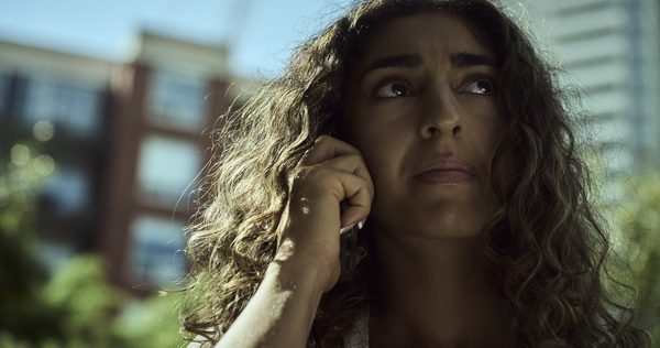 The Actor outdoors with the phone to her ear, looking away past the camera.