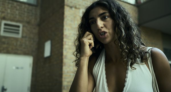The Actor on the phone against a brick wall, caught mid-sentence.