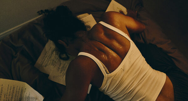 The Actor face down on a bed, script pages scattered across her back.
