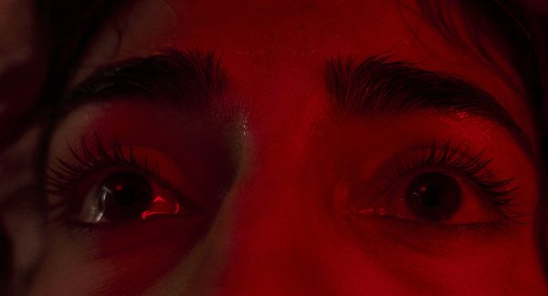 Extreme close-up of the Actor's eyes, wet and lit hard red.